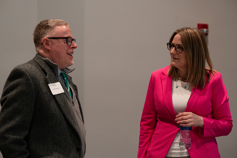 Candid photo of CEO, Yvonne Fleener, and Board Chair, Bill McElhone, visiting at the breakfast event.