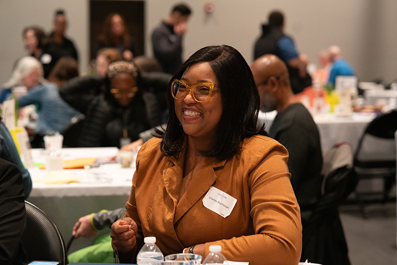 Candid photo of a breakfast event attendee, smiling, with other guests in the background.