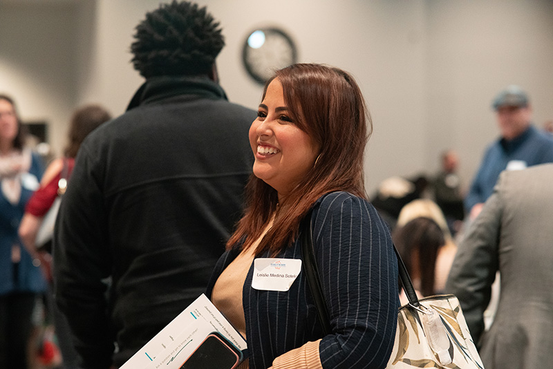 Candid photo of a breakfast event attendee, smiling, with other guests in the background.
